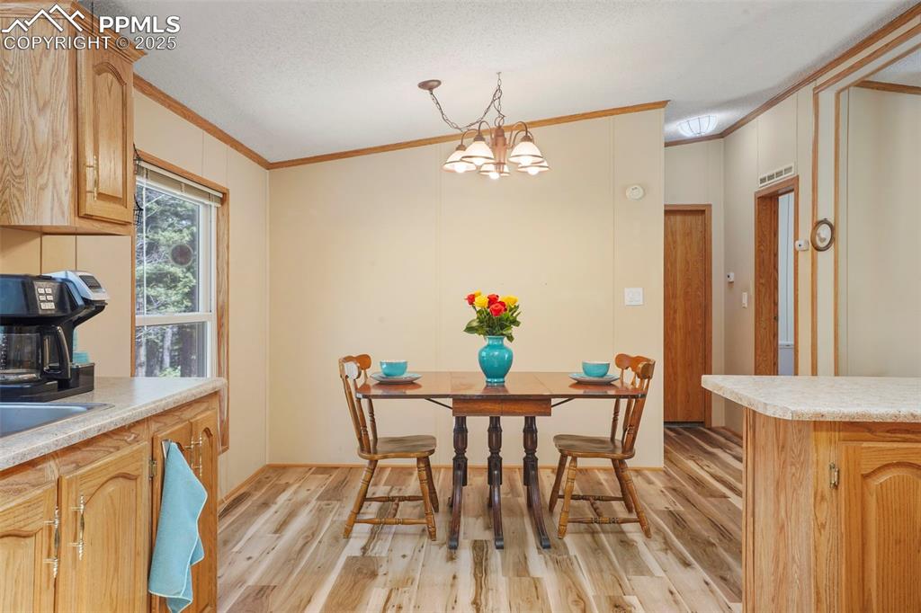 Image 8 of 29: Dining space with ornamental molding, light wood-style flooring, a chandeli