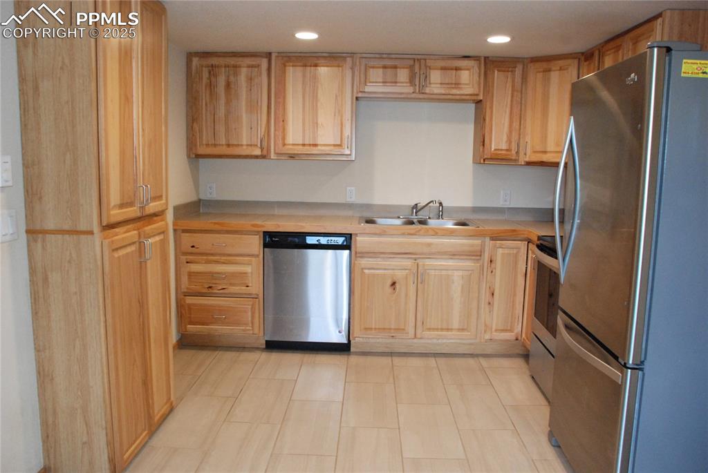 Image 12 of 37: The kitchen features natural wood cabinets and ceramic tile flooring.