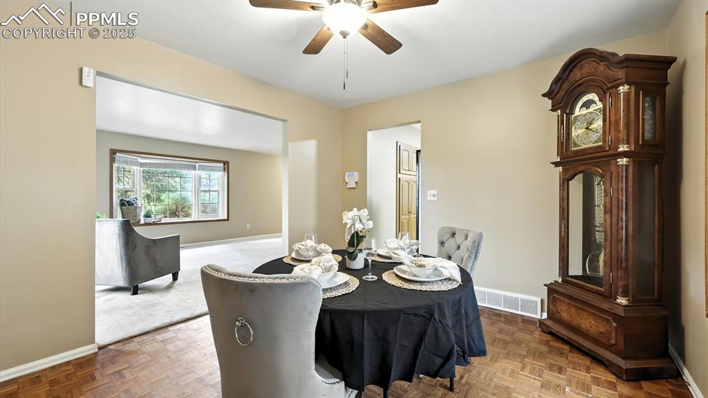 Image 10 of 50: The formal dining room boasts hardwood floors, a lighted ceiling fan, & bay