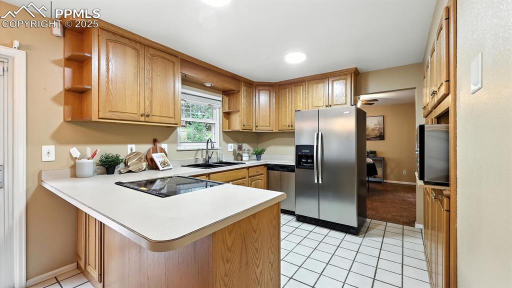 Image 13 of 50: The Eat-In Kitchen includes tile flooring, wood cabinetry, & modern applian