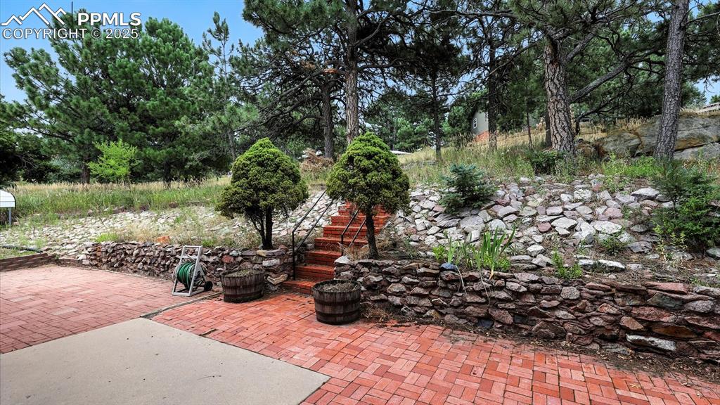 Image 18 of 50: Expanded concrete and brick patio off the Dining Nook with stairs to the st