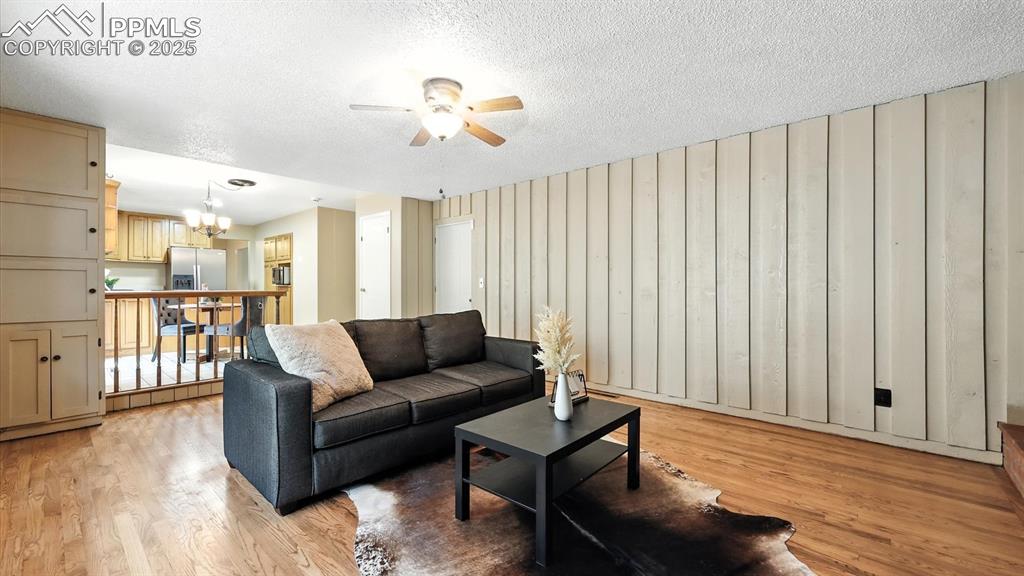 Image 22 of 50: Family Room with wood floor and lighted ceiling fan.