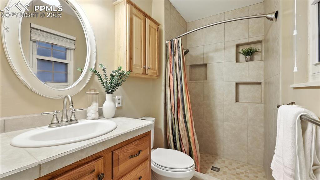 Image 35 of 50: Ensuite Shower Bathroom in the Primary Suite with a vanity, mirror, and til
