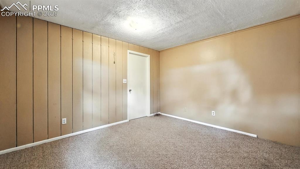 Image 41 of 50: Basement Bedroom #4 with lighted ceiling fan, paneled walls, and neutral ca