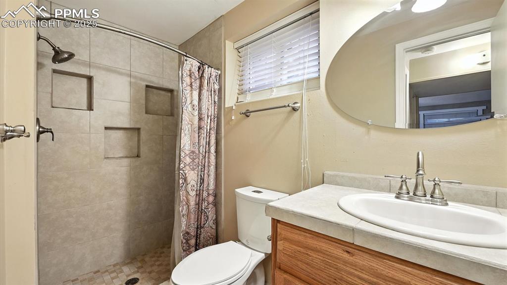 Image 42 of 50: Basement Shower Bathroom with vanity, mirror, and tiled shower.