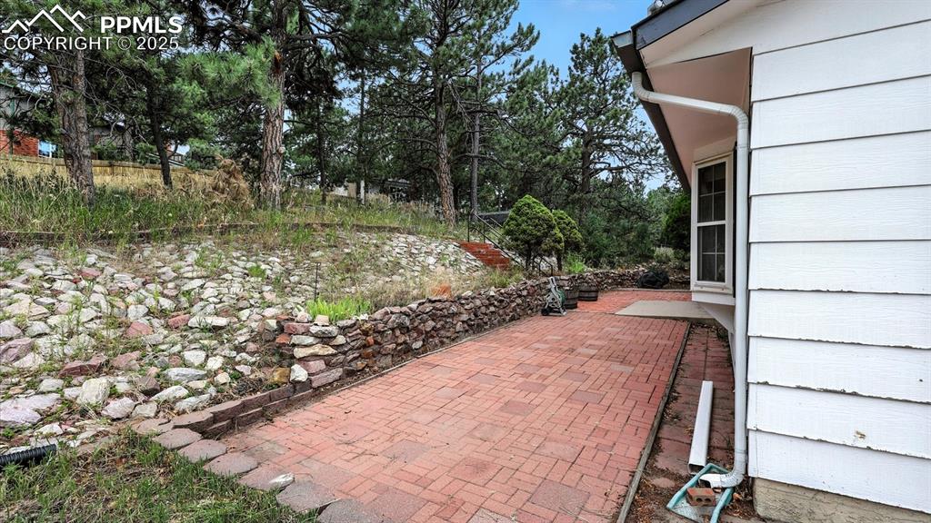 Image 48 of 50: Beautifully treed backyard with brick and concrete patio.