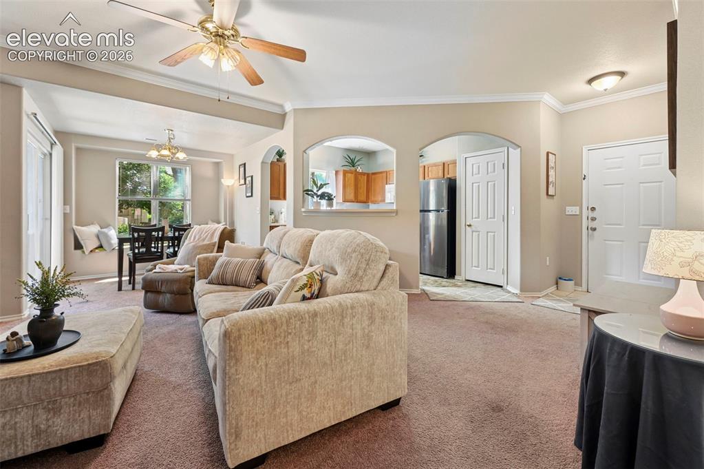 Image 10 of 36: Spacious living area featuring neutral-toned walls, crown molding, and a ce
