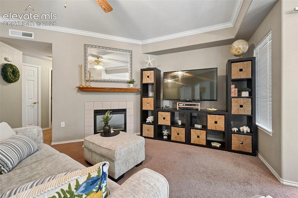Image 13 of 36: Living area featuring a fireplace with a tile surround and a wood mantel