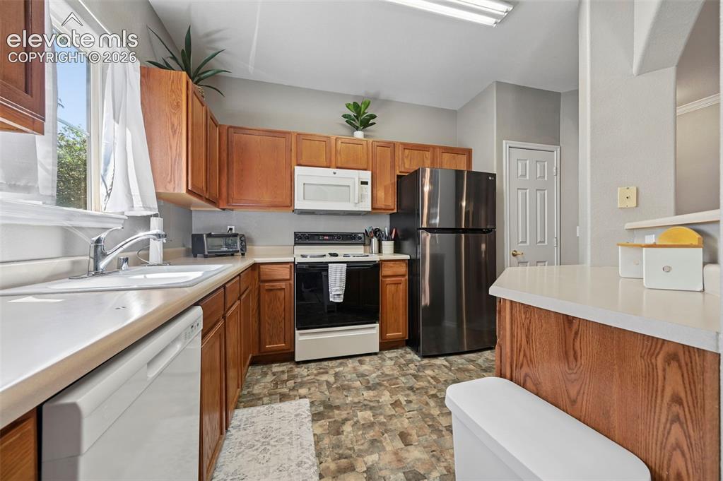Image 14 of 36: Kitchen featuring wood cabinetry, light-toned countertops, a stainless stee