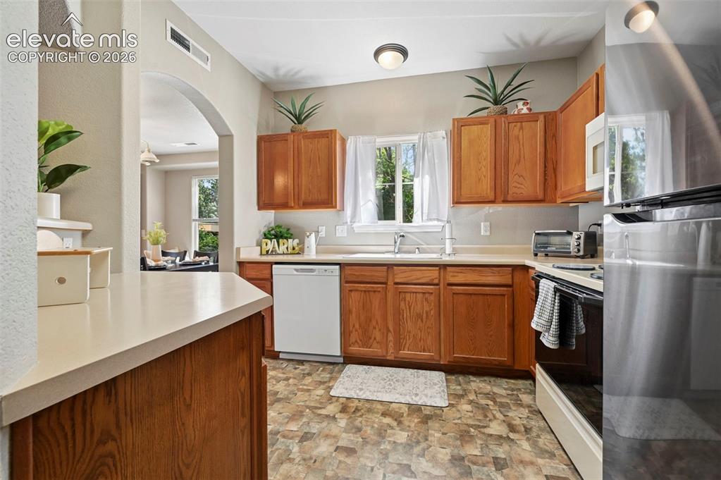 Image 17 of 36: Kitchen featuring wood-finish cabinetry, light-toned countertops, and a whi