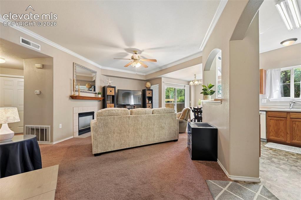 Image 19 of 36: Expansive living area featuring crown molding, a ceiling fan, and a tiled f