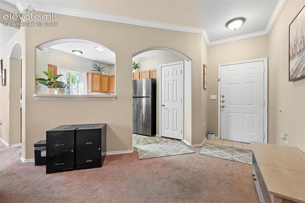 Image 21 of 36: Entryway featuring an arched pass-through window to the kitchen, a paneled