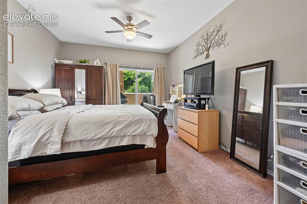 Image 25 of 36: Carpeted bedroom featuring a ceiling fan with integrated lighting, a slidin