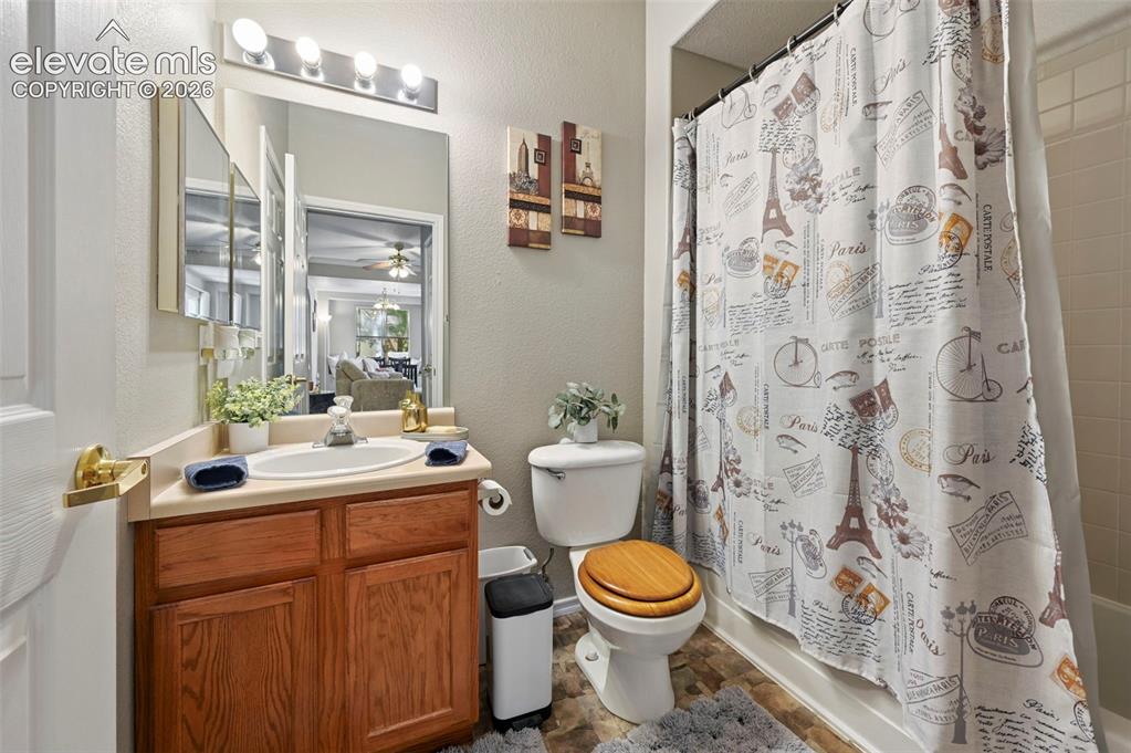 Image 27 of 36: Bathroom featuring a wood-finish vanity with a single basin sink, a large w