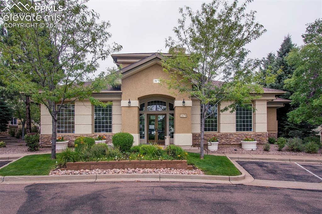 Image 4 of 36: Stucco and stone facade building with arched entry, grid-pattern windows, a