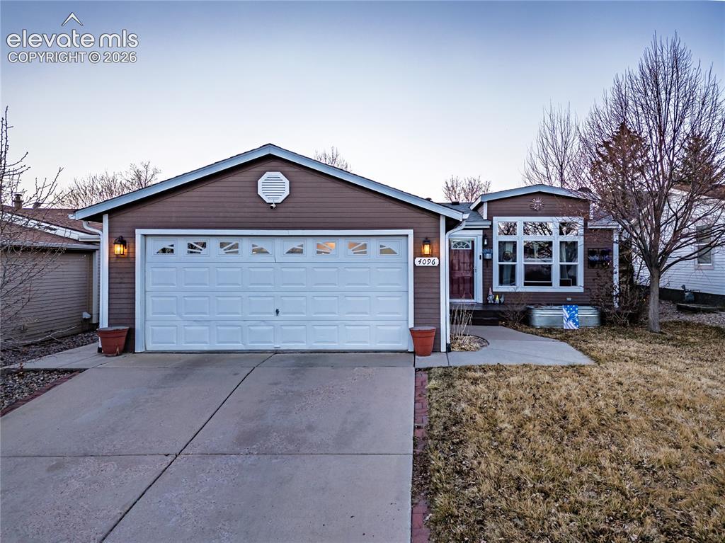 Caption: Single-story exterior with brown siding, an attached garage, a concrete driveway, and a front entry 