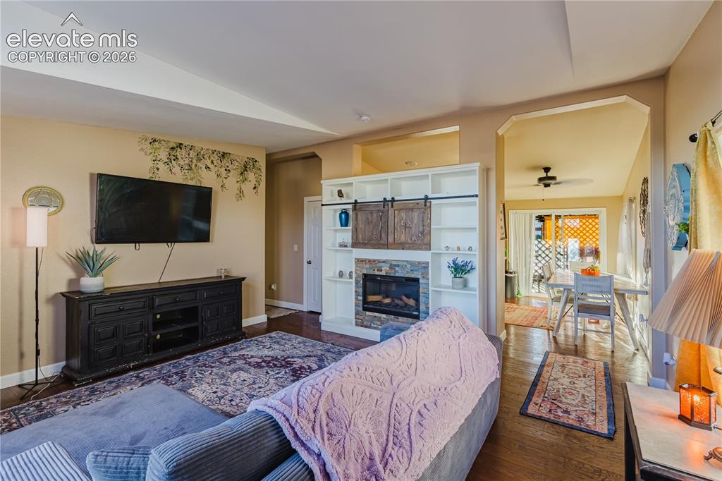 Image 10 of 30: Living area featuring a built-in fireplace with stone surround, custom shel