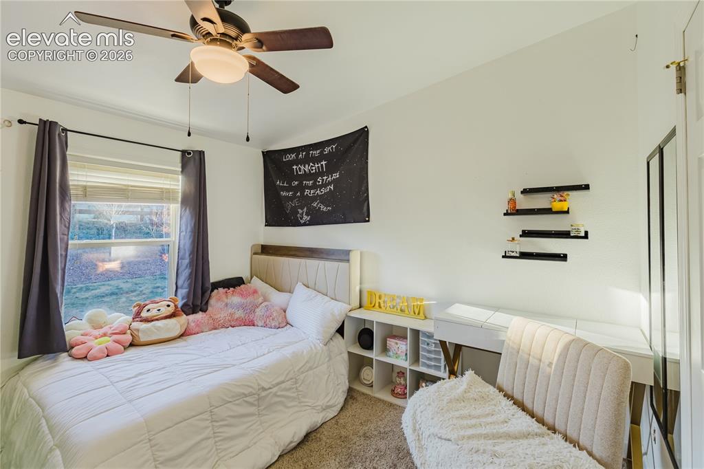 Image 15 of 30: Bedroom featuring a ceiling fan with integrated lighting, a window with hor