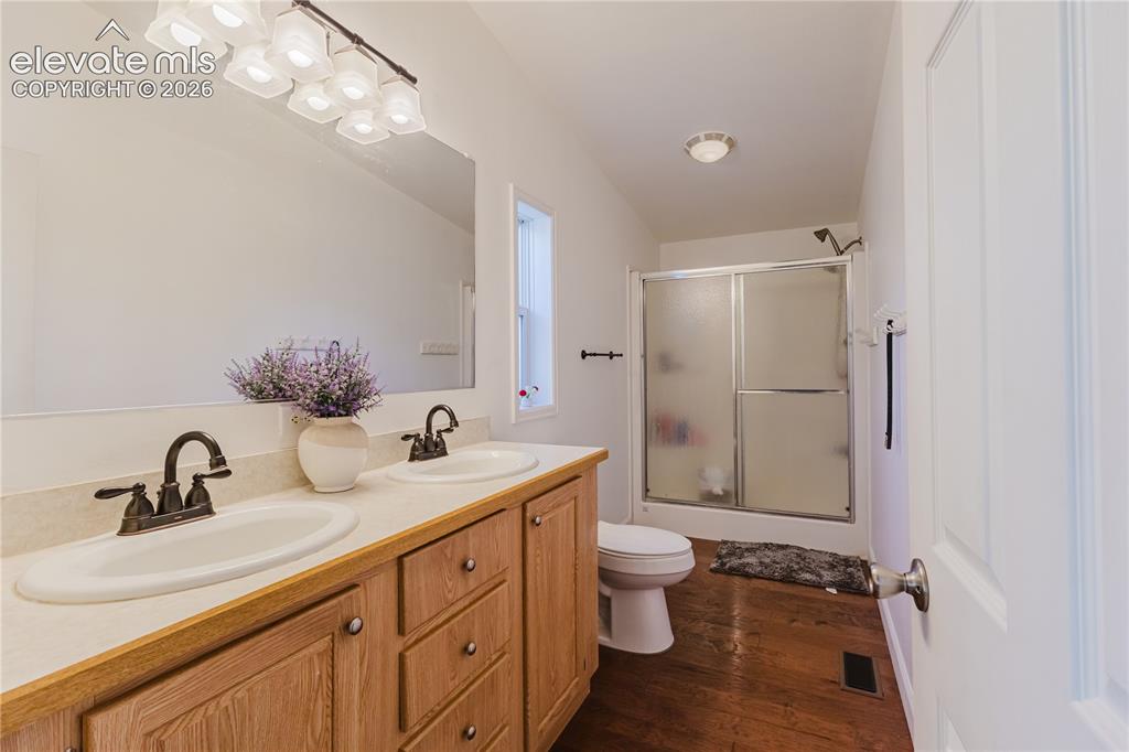 Image 21 of 30: Bathroom featuring a double vanity with light wood cabinetry, dual oval sin