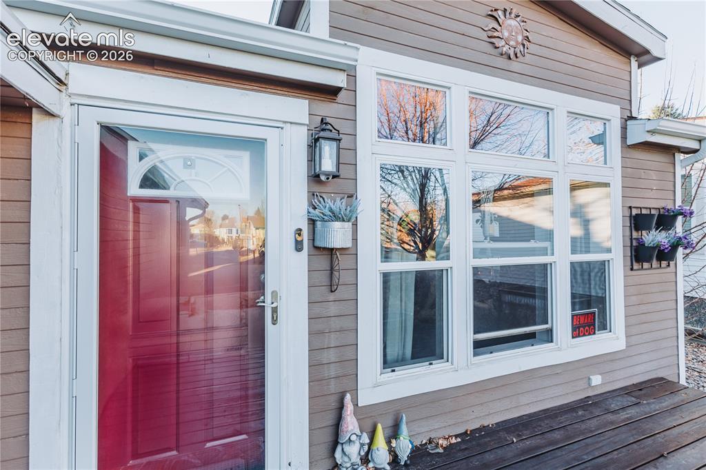 Image 25 of 30: Red entry door with an arched transom window, storm door, and adjacent wall