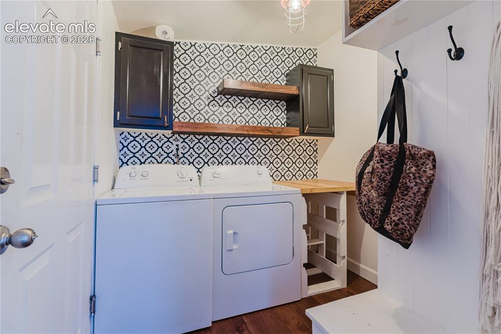 Image 26 of 30: Laundry area featuring patterned wall tile, dark cabinetry, and two wood-fi