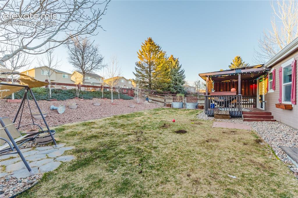 Image 30 of 30: Expansive backyard featuring a covered patio, terraced landscaping, and a f