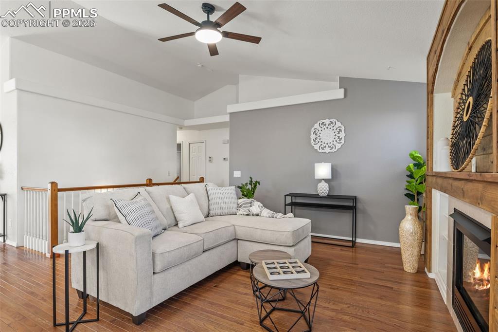 Image 11 of 50: Living area featuring ceiling fan, a lit fireplace, vaulted ceiling, and wo