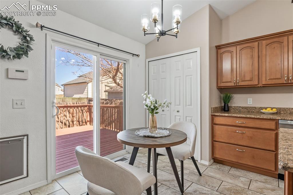 Image 12 of 50: Dining area with suspended lighting, lofted ceiling, and light tile pattern