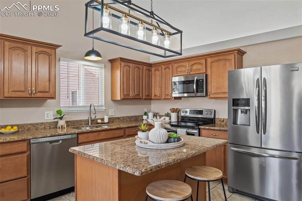 Image 14 of 50: Kitchen with stainless steel appliances, wood finish cabinetry, hanging lig