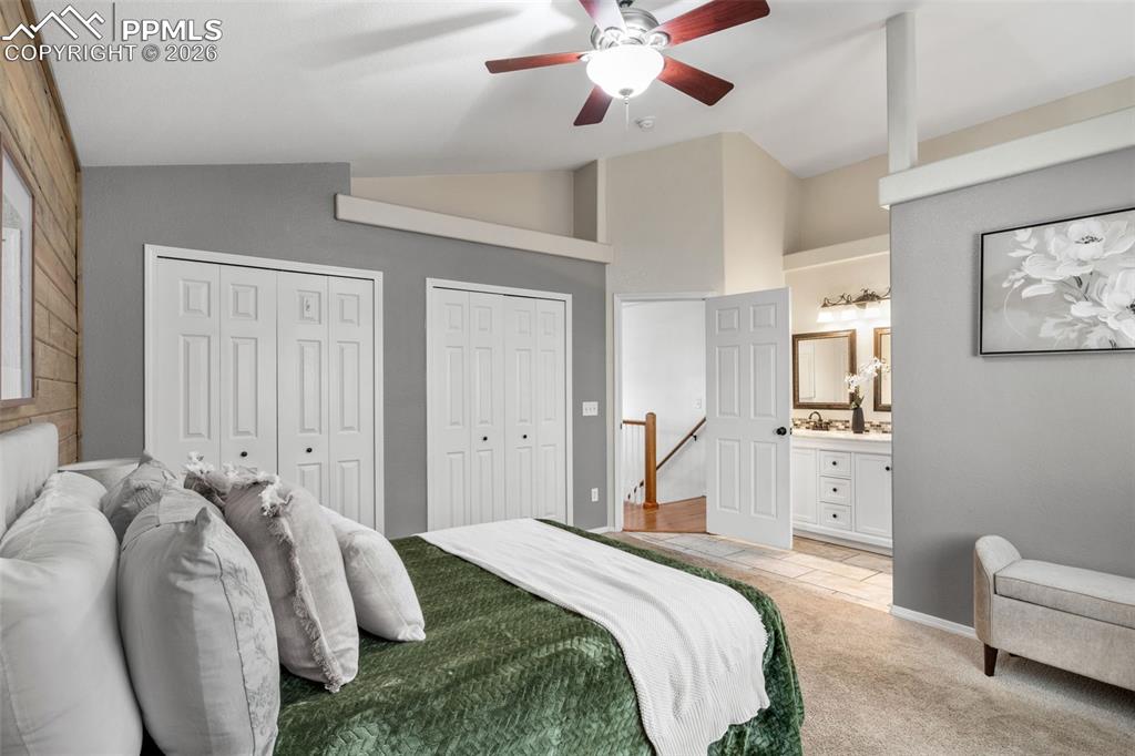 Image 19 of 50: Bedroom featuring lofted ceiling, multiple closets, light colored carpet, a