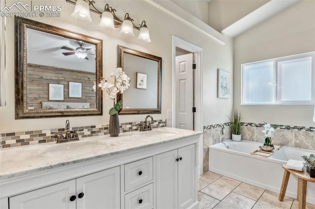 Image 21 of 50: Full bathroom featuring a bath, double vanity, and a ceiling fan