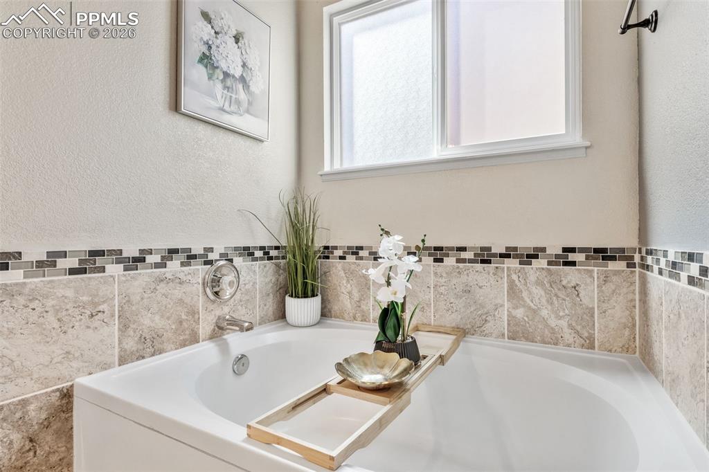 Image 22 of 50: Bathroom with a bath and a textured wall