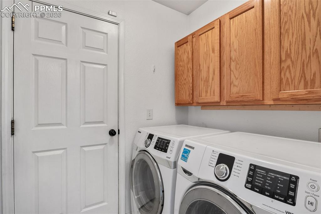 Image 28 of 50: Laundry room with cabinet space and washing machine and dryer
