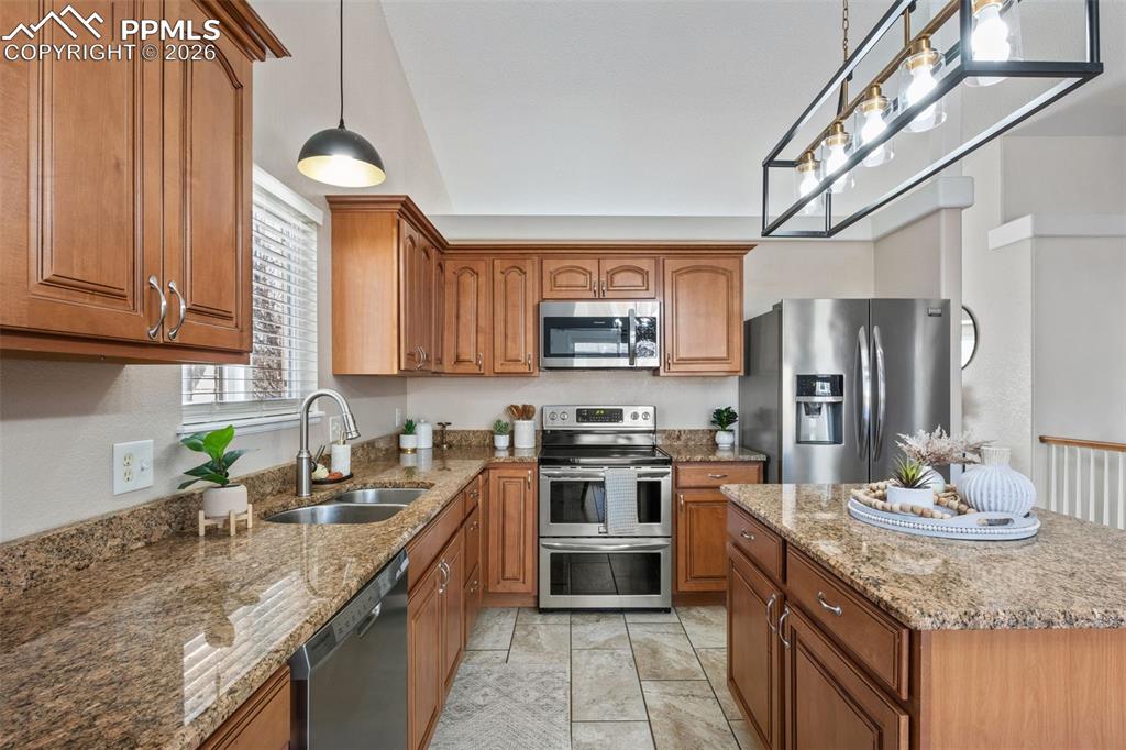 Image 3 of 50: Kitchen with stainless steel appliances, wood finish cabinets, light stone 