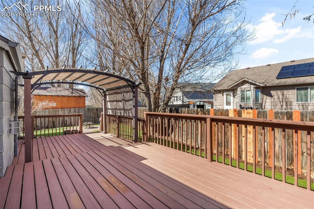 Image 36 of 50: Wooden terrace with a fenced backyard