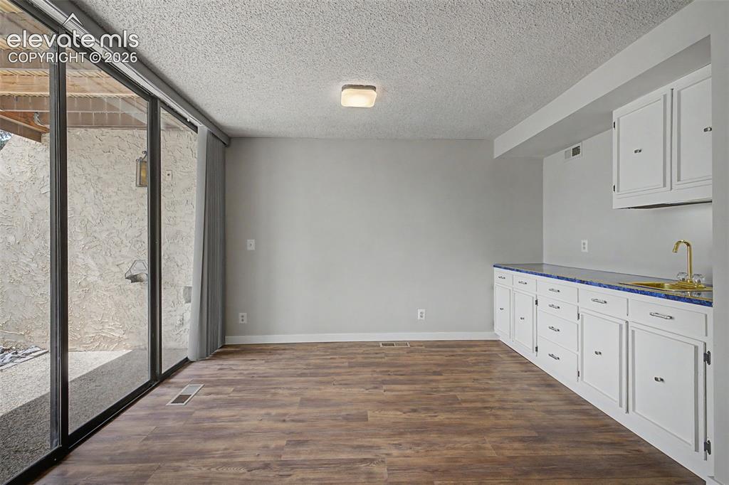 Image 17 of 29: Wet bar in the living room with expansive windows and walk out to the beatu