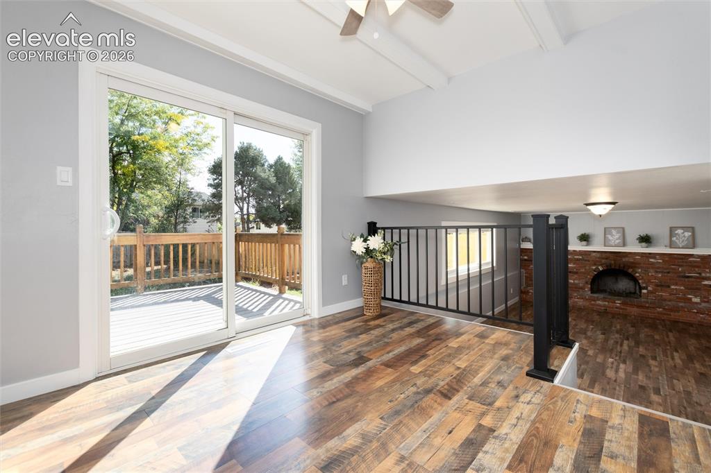 Image 10 of 47: Wood-finish flooring, sliding glass door to a wood deck, exposed beam ceili