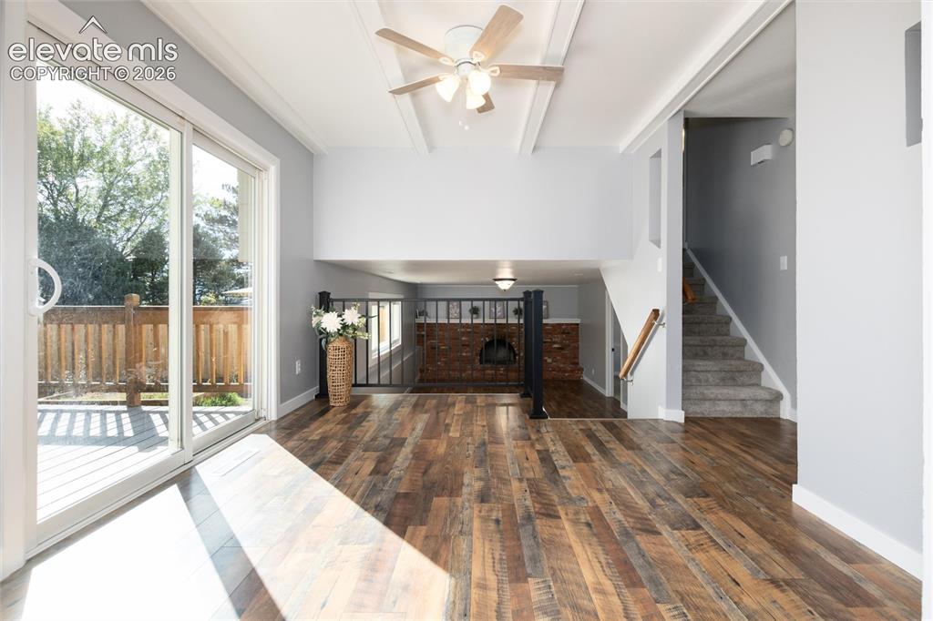 Image 11 of 47: Wood-finish flooring, sliding glass door, deck, ceiling fan, and staircase 