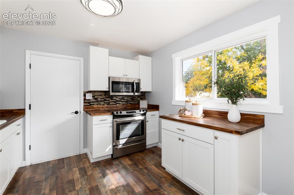 Image 15 of 47: Wood-finish flooring with white cabinetry, stainless steel appliances, and