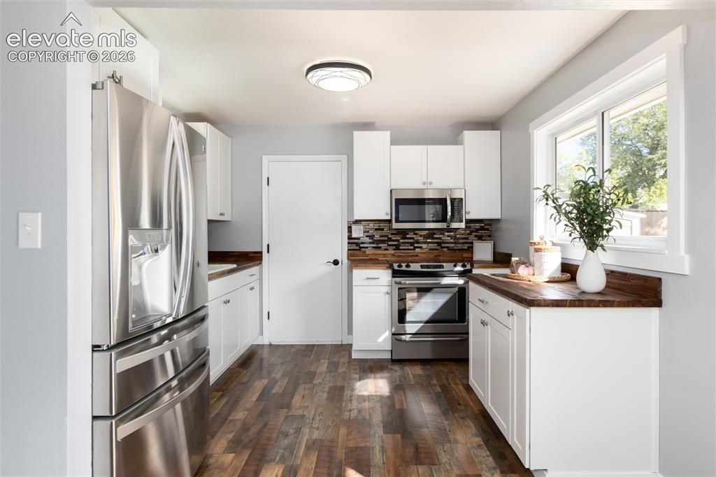 Image 16 of 47: Kitchen featuring wood-finish flooring, white cabinetry, stainless steel ap