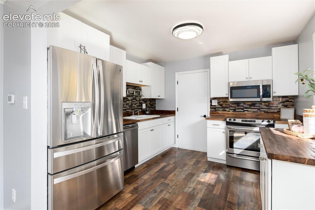 Image 17 of 47: Kitchen featuring stainless steel appliances, white cabinetry, wood-finish 