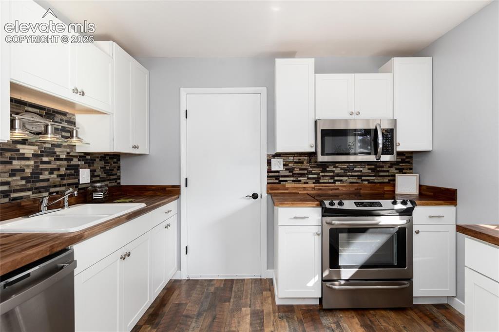 Image 18 of 47: Wood-finish flooring with white cabinetry, wood-finish countertops, and a f
