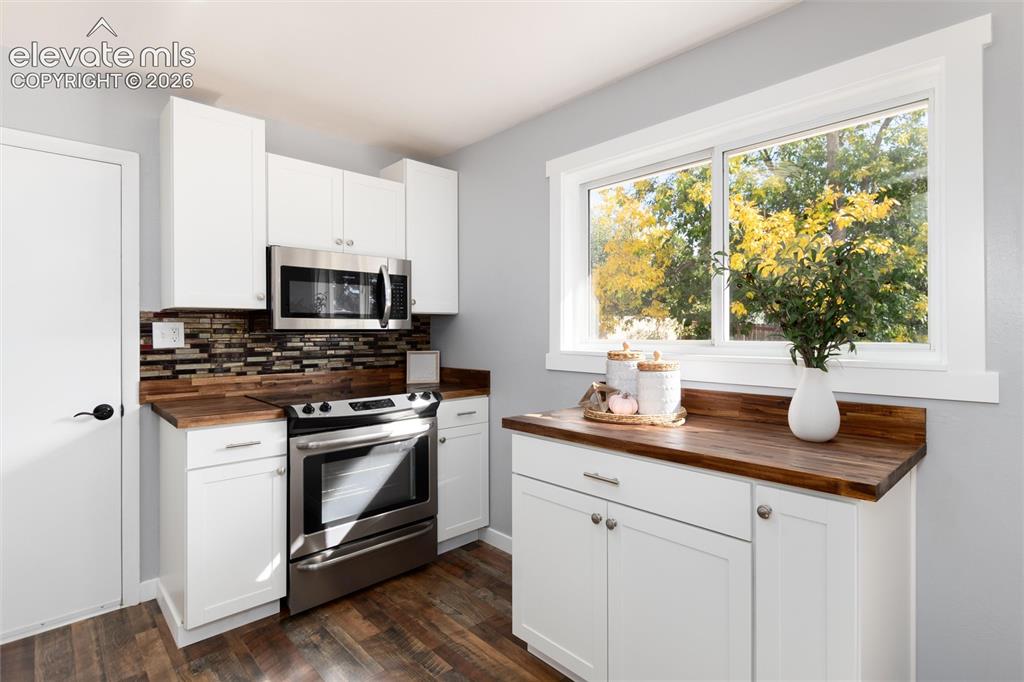 Image 19 of 47: Kitchen featuring wood-finish countertops, white cabinetry, stainless steel