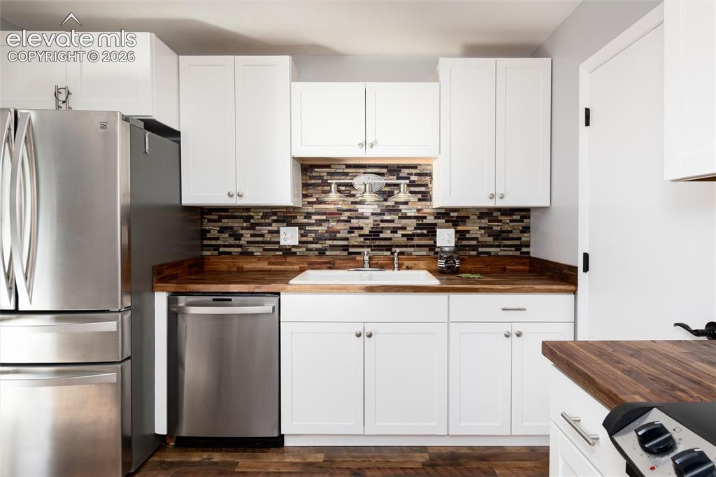 Image 20 of 47: White cabinetry with silver-tone hardware, wood-finish countertops, tile ba