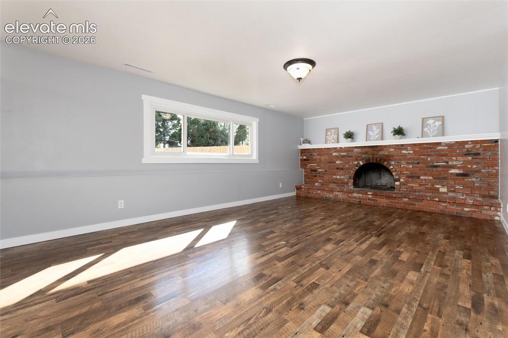 Image 22 of 47: Wood-finish flooring, brick fireplace with arched opening, white fireplace