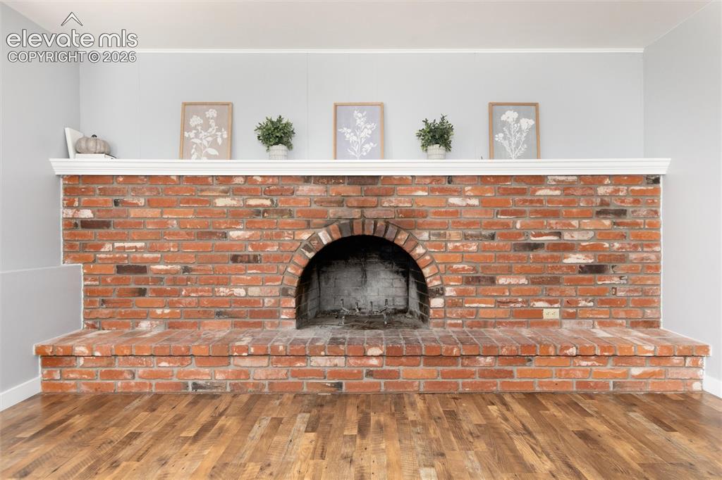 Image 24 of 47: Brick fireplace with an arched firebox, substantial brick hearth, and a whi