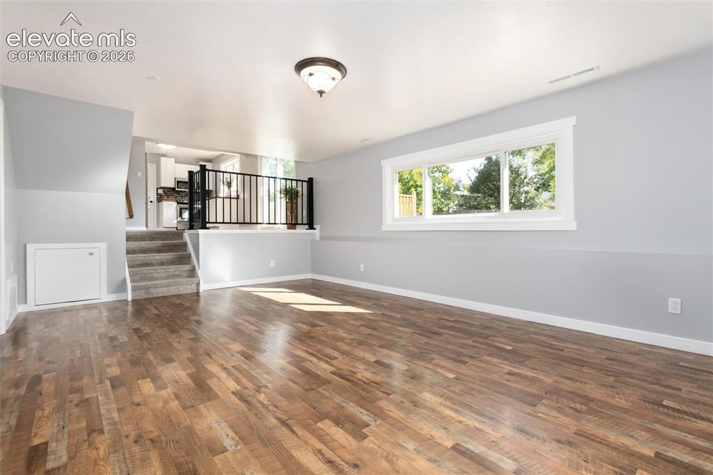 Image 25 of 47: Wood-finish flooring, recessed window, and staircase with carpeted treads