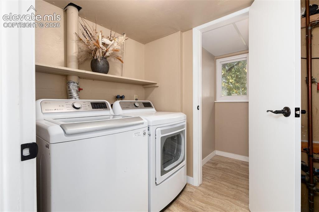 Image 26 of 47: Dedicated laundry area with built-in shelving, durable flooring, and a wind