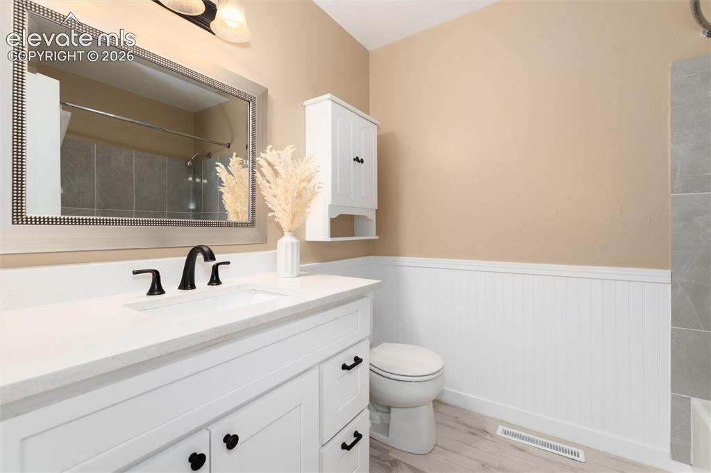 Image 33 of 47: White vanity with a solid surface countertop, black fixtures, and a framed 