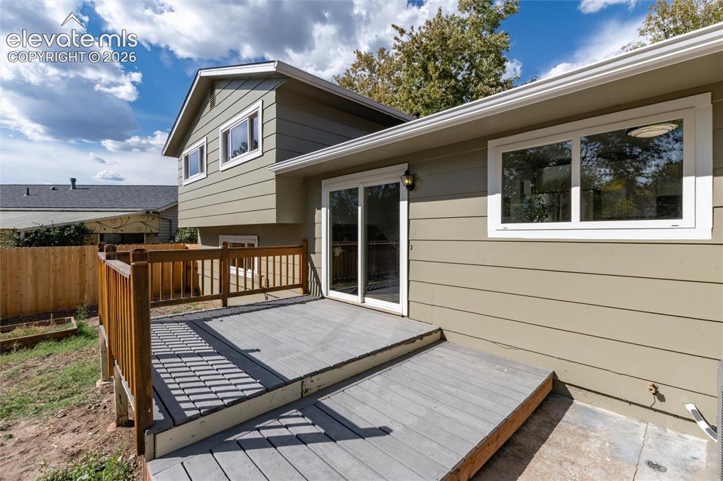 Image 35 of 47: Multi-level deck with wood railing, sliding glass door access, and ground-l